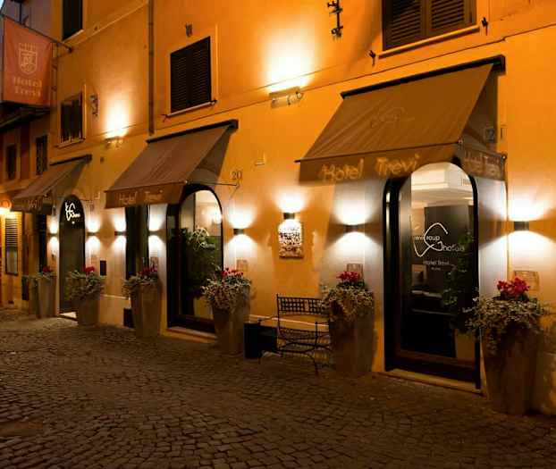 Hotellingång med välkomnande belysning, blomkrukor och skyltar. (AI-genererad text)