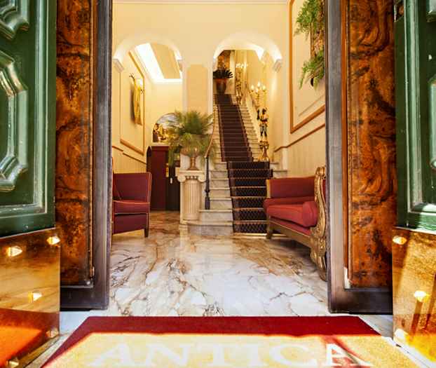 Entré till elegant hotell med marmorgolv, röda stolar och trappa. (AI-genererad text)