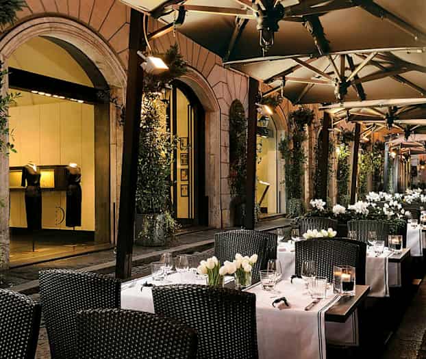 Uteservering med bord, vita dukar och blomdekorationer. (AI-genererad text)