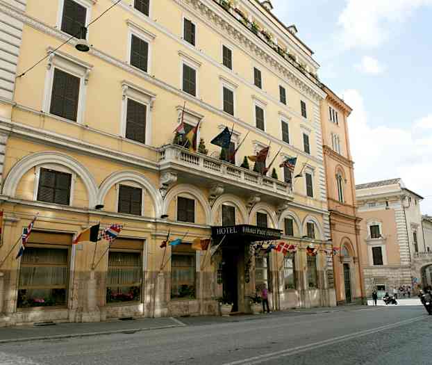 Ett flervåningshus med en hotellskylt och flaggor från olika länder. (AI-genererad text)