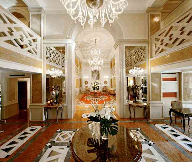 Ett elegant hotellfoajé med kristallkronor, speglar och en centralbord med blommor. (AI-genererad text)