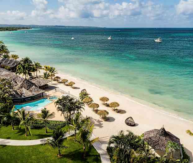 En strand med parasoller och en resort med simbassäng. (AI-genererad text)