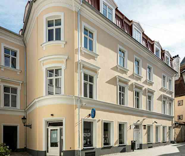 En beige byggnad med vita detaljer och röda tak i ett stadsområde. (AI-genererad text)