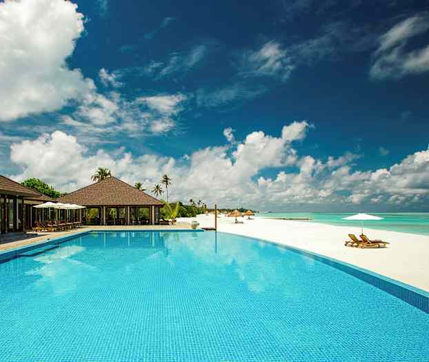 En lyxig resort med pool bredvid en vit sandstrand. (AI-genererad text)