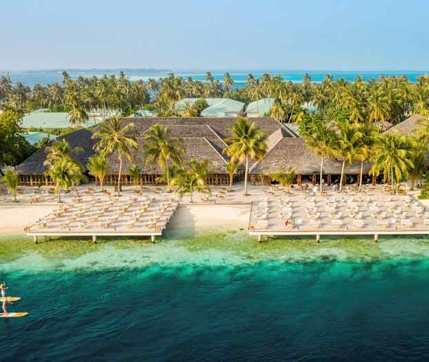 Hotellanläggning vid stranden med solstolar och turkosblått vatten. (AI-genererad text)