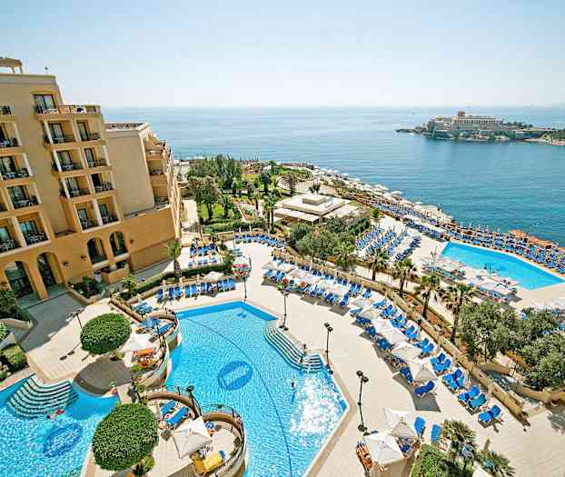 En hotellanläggning med pooler, solstolar och parasoller, samt havsutsikt. (AI-genererad text)