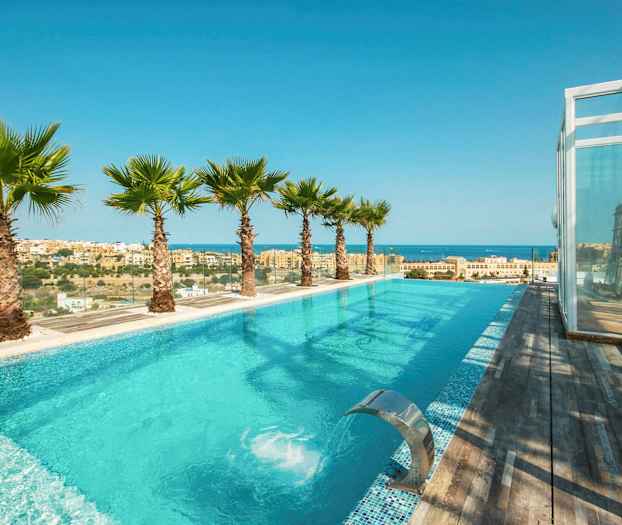 En infinitypool med utsikt över havet och staden, omgiven av palmer och trädeck. (AI-genererad text)