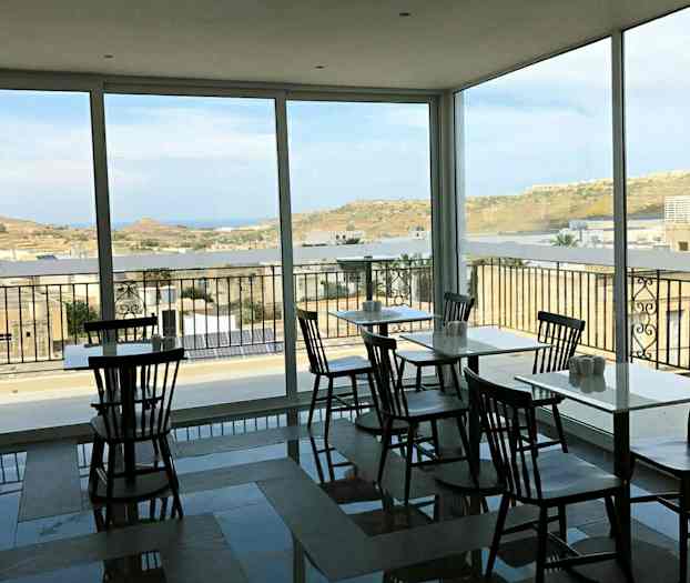 Ett café med stora fönster och utsikt över ett landskap. (AI-genererad text)