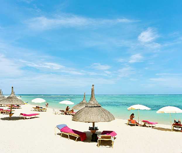 En strand med parasoller och solsängar vid havet. (AI-genererad text)