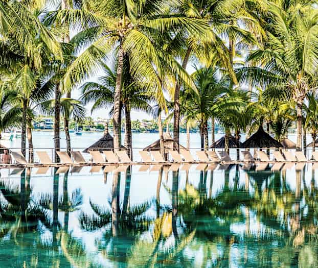 Solstolar och palmer vid en pool i tropisk miljö. (AI-genererad text)