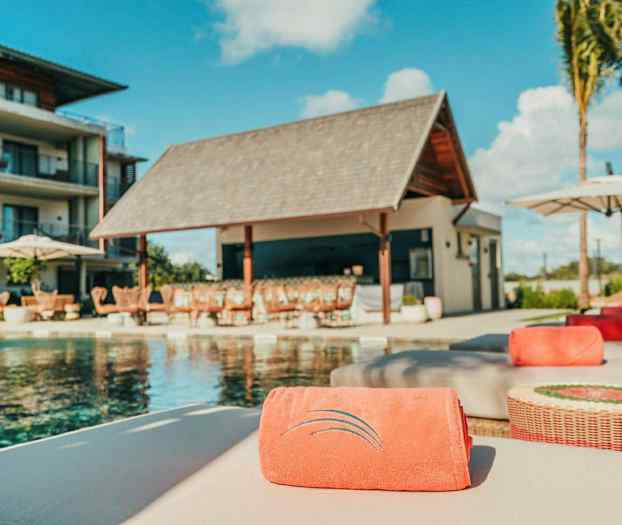 Poolområde med solstolar och en byggnad i bakgrunden. (AI-genererad text)