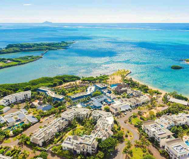 Flygfoto av resortområde nära en strand med blått hav. (AI-genererad text)