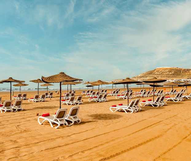 Solstolar med parasoller på sandstrand. (AI-genererad text)