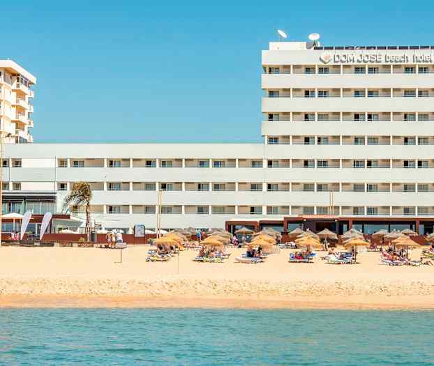 Hotell vid stranden med parasoller och solstolar. (AI-genererad text)