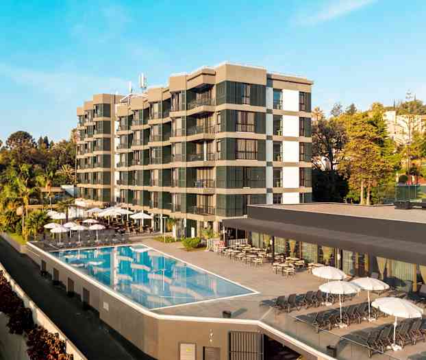 Bild av ett hotell med utomhuspool och solstolar, omgiven av träd och vegetation. (AI-genererad text)