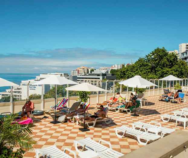 Solterrass med solstolar och parasoller, med utsikt över havet. (AI-genererad text)