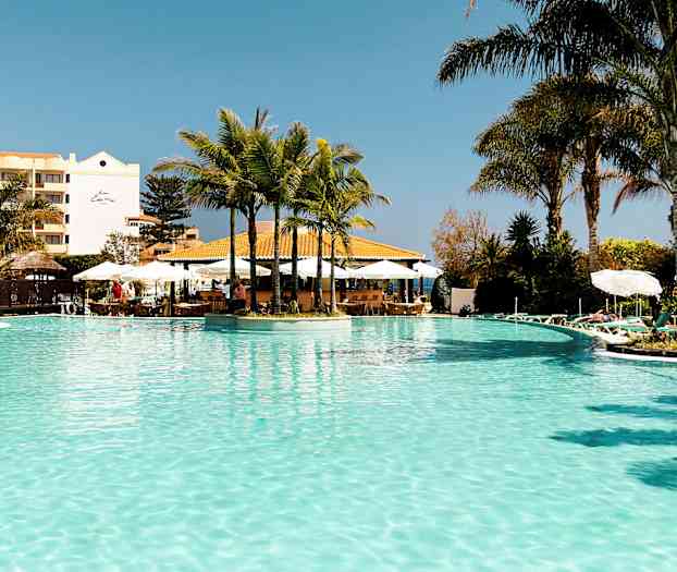 En utomhuspool med palmer och solstolar runt omkring. (AI-genererad text)