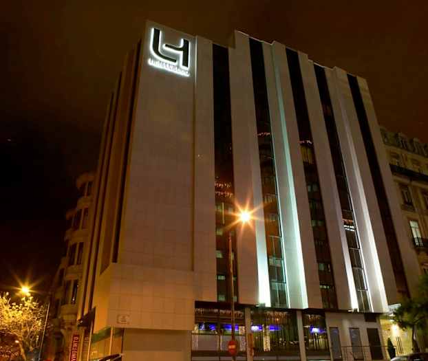 Ett hotell med modernt yttre fotograferat på natten. Byggnadens fasad är belyst. (AI-genererad text)