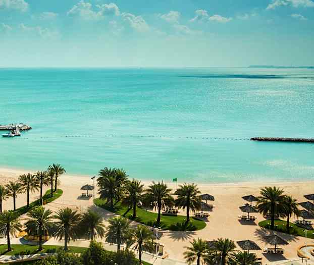 Sandstrand med vita parasoller, palmträd och turkost vatten. (AI-genererad text)