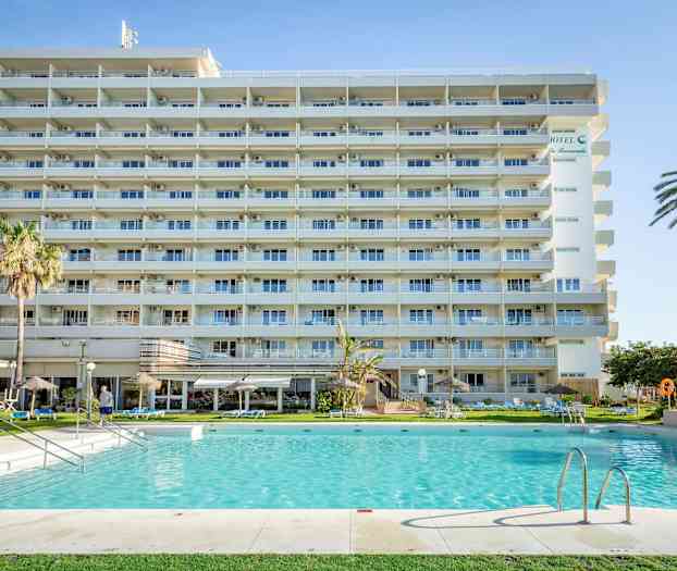 Ett flerbostadshotell med balkonger framför en swimmingpool och omgivande trädgård. (AI-genererad text)