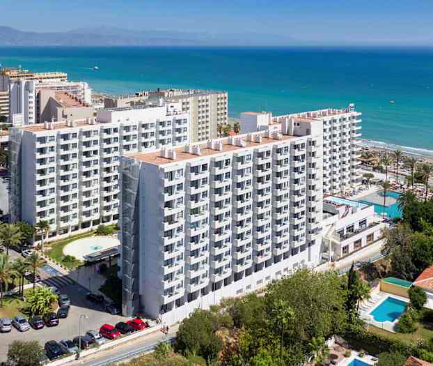 Bild av ett hotell i flera våningar vid kusten med havet synligt i bakgrunden. (AI-genererad text)