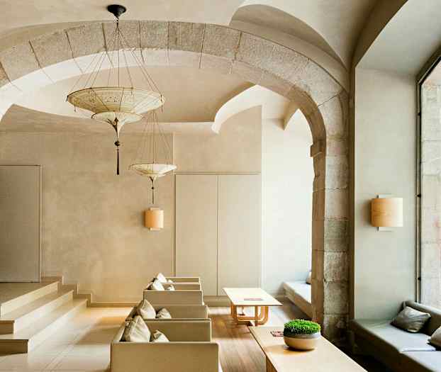 Ett elegant inrett rum med valvbågar, moderna möbler, och stora fönster som vetter mot en gata. (AI-genererad text)