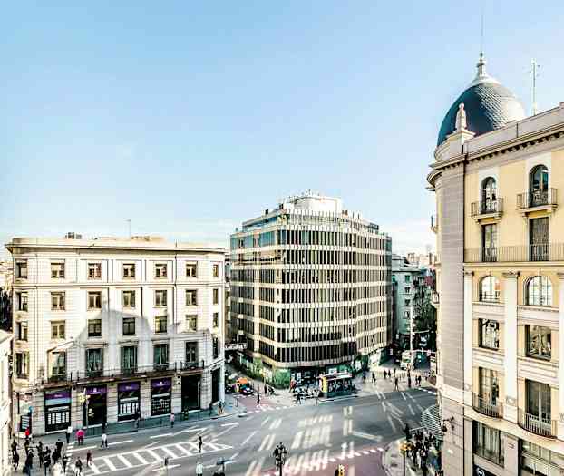 En stadsgata med flera omgivande byggnader i olika arkitektoniska stilar. (AI-genererad text)