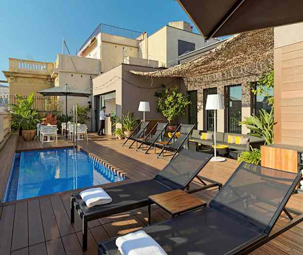 En takterrass med solstolar, ett litet rektangulärt poolområde, växter samt bord med parasoll. (AI-genererad text)