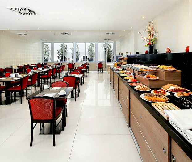 En restaurang med en lång buffé fylld med mat samt bord och stolar med röda sittdynor. (AI-genererad text)