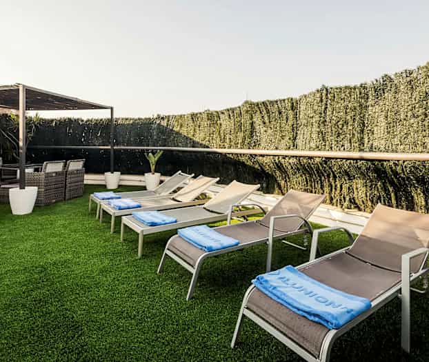 Solstolar och fåtöljer i en trädgårdsmiljö med konstgräs. (AI-genererad text)