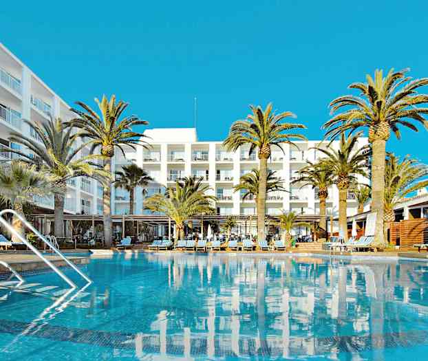 Bilden visar en pool framför ett hotell med flera våningar, omgiven av palmer under en klarblå himmel. (AI-genererad text)