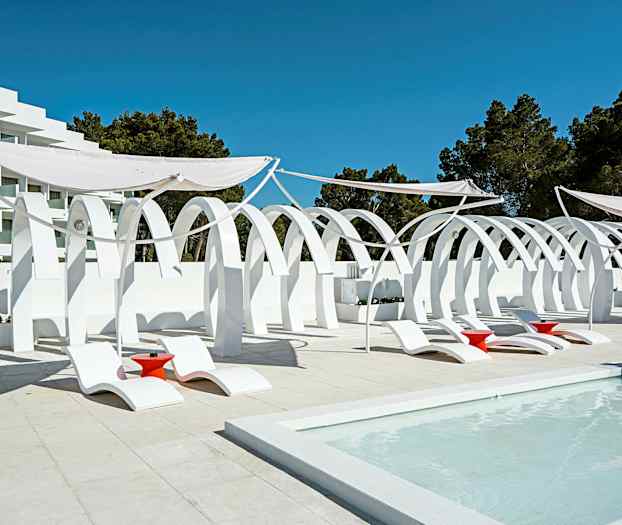 Vit arkitektur med bågar, samt solstolar och röda bord vid en pool. (AI-genererad text)