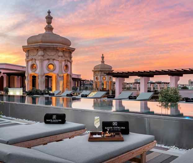 Utsikt över takpool med solbäddar och dekorativa kupoler i solnedgång. (AI-genererad text)