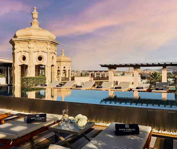 Takpool med solstolar och utsikt över staden. Ornamenterad arkitektur i bakgrunden. (AI-genererad text)