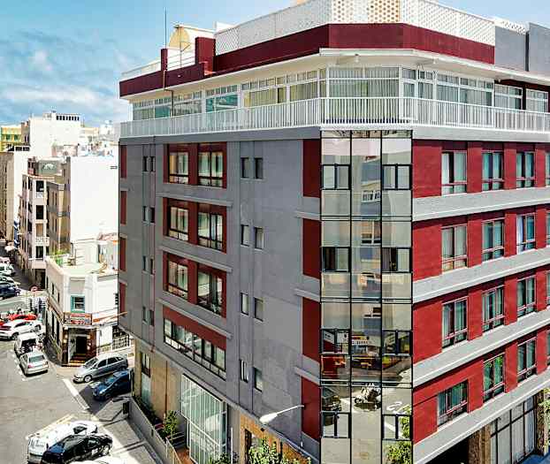 Bild av en stadsbyggnad med röda och grå fasader nära havet. (AI-genererad text)