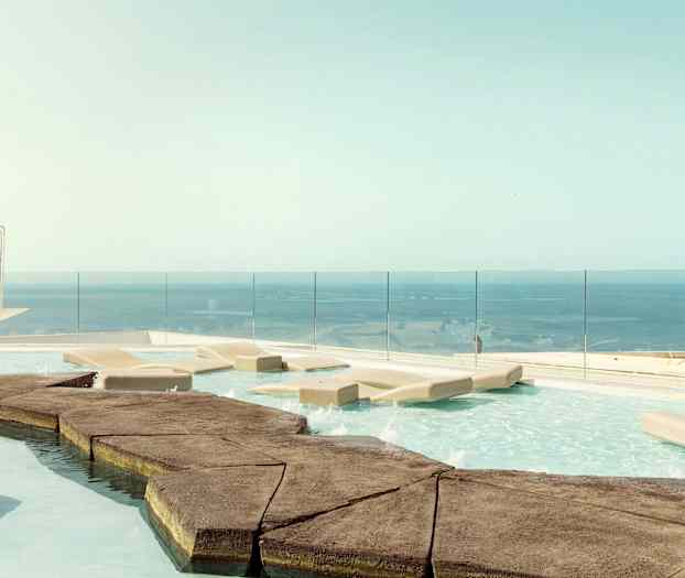 En infinitypool med liggstolar och utsikt över havet. (AI-genererad text)