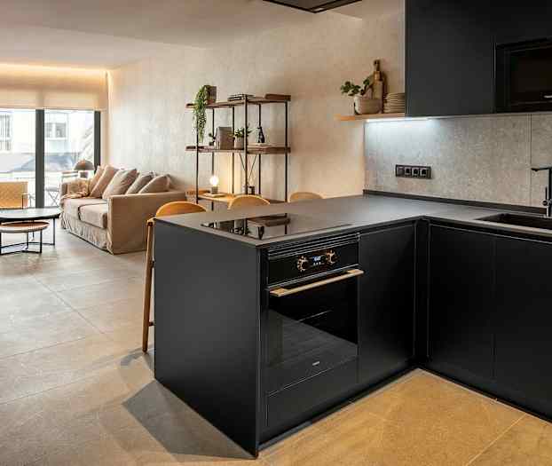 Bild av ett modernt vardagsrum och kök med stilren inredning. Visar en grå köksö och en soffa i bakgrunden. (AI-genererad text)