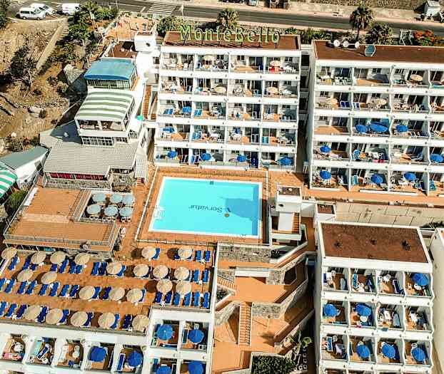 Flygvy över hotell Montebello med pool och solstolar. (AI-genererad text)