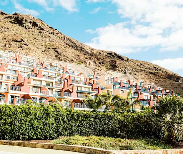 Flera radhus med balkonger längs en sluttning. (AI-genererad text)