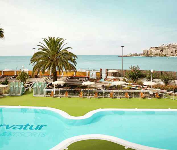 En pool med utsikt över havet och en solig terrass med solstolar. (AI-genererad text)