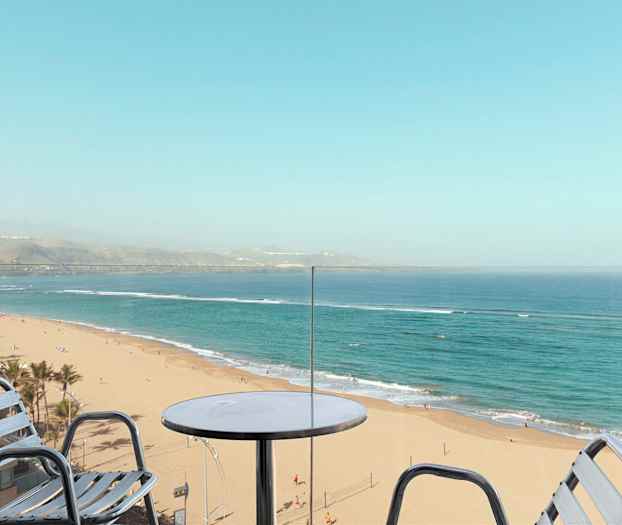 Utsikt från en balkong mot en sandstrand och hav. (AI-genererad text)