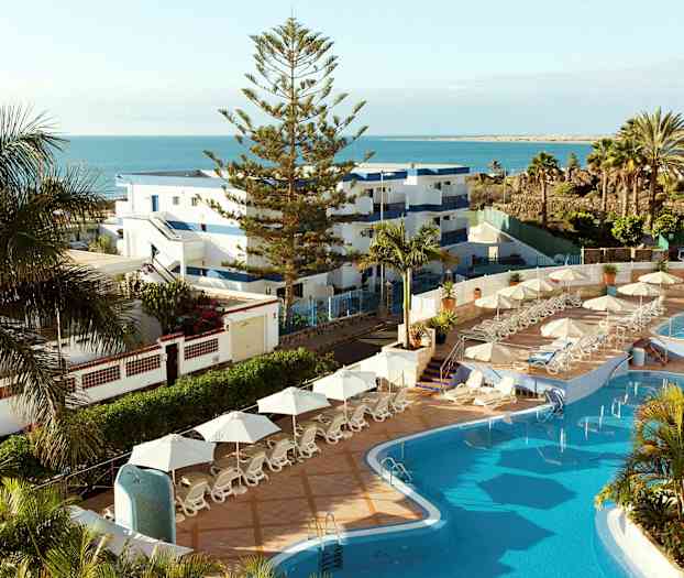 Bild på ett hotellområde med pool, solstolar och utsikt över havet. (AI-genererad text)