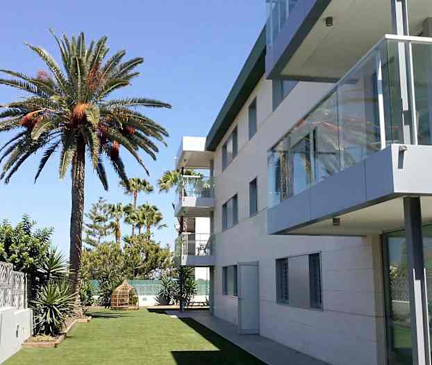 Modern byggnad bredvid en gräsmatta med palmer. (AI-genererad text)