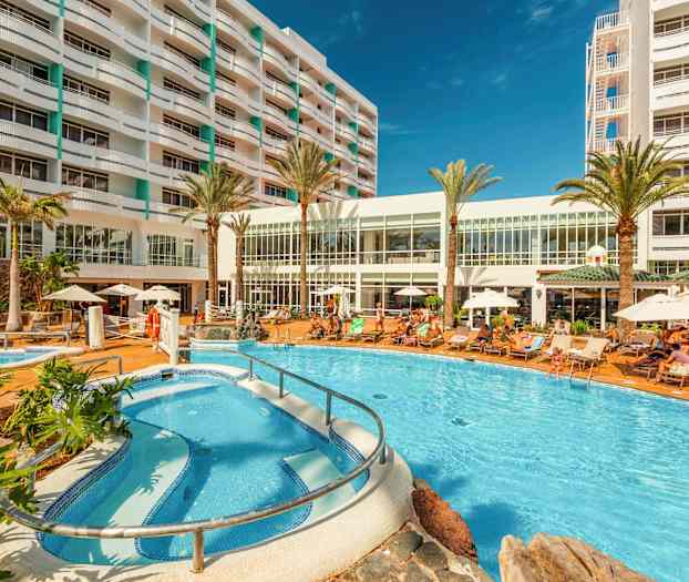 Hotellområde med pool, solstolar och byggnad i bakgrunden. (AI-genererad text)