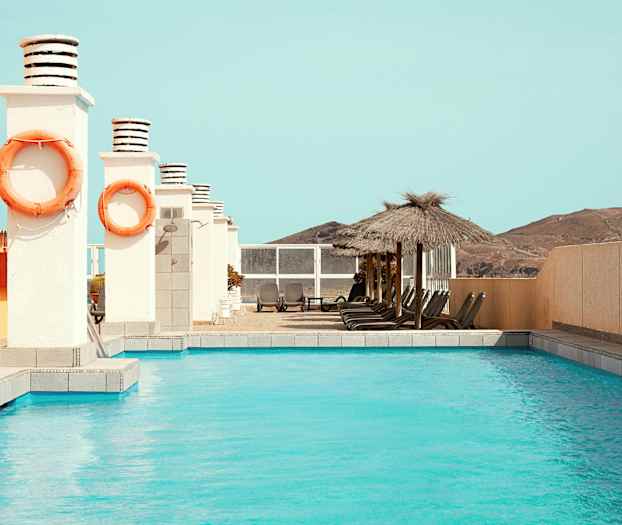 Utomhuspool med solsängar och parasoll vid sidan. (AI-genererad text)