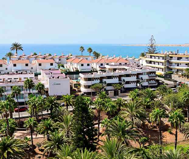 Utsikt över bostäder med trädgårdar och hav i bakgrunden. (AI-genererad text)