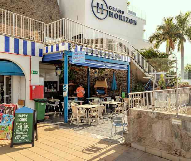 Bild av en butik och ett café med bord och stolar utomhus. (AI-genererad text)