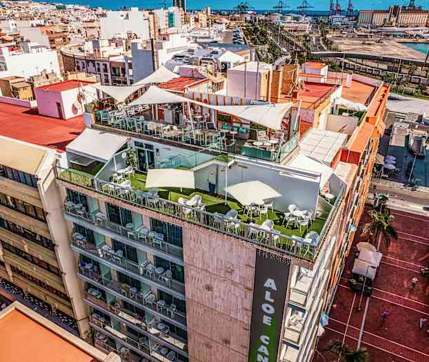 En byggnad med terrasser vid toppen, omgiven av en stad och med havet i bakgrunden. (AI-genererad text)