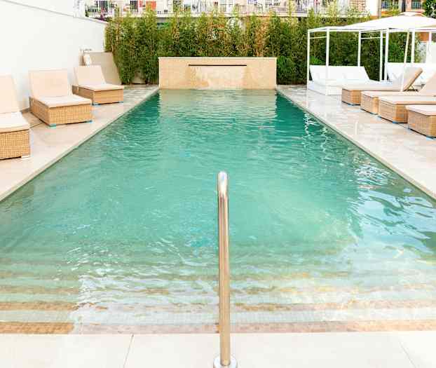 En swimmingpool med solstolar vid kanten. (AI-genererad text)