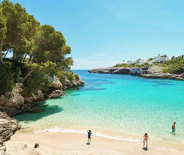 En vik med turkost vatten, sandstrand och omgivande klippor. (AI-genererad text)